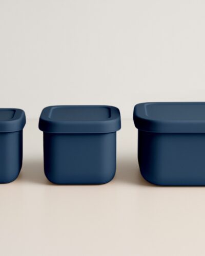 Drie marineblauwe snackdoosjes in een rechte lijn naast elkaar, deksels gesloten